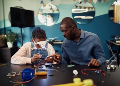 portrait-black-teen-girl-building-robot-engineering-class-with-male-teacher-helping